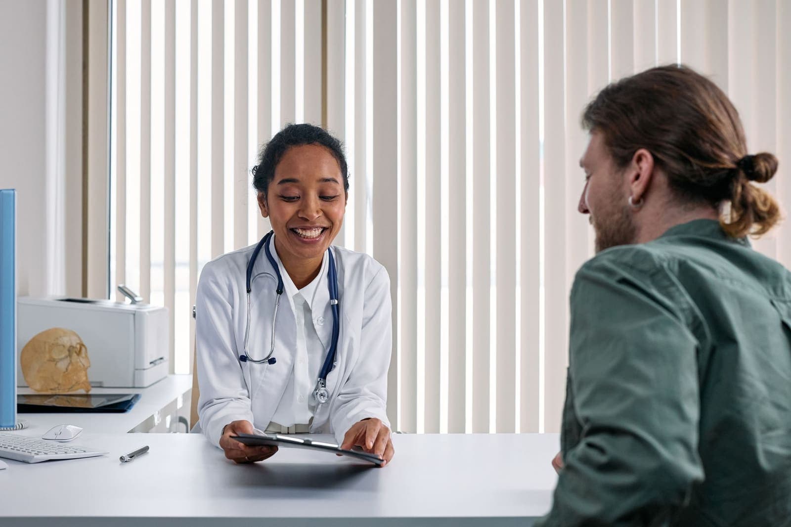 A doctor smiling at a patient across a desk during a consultation