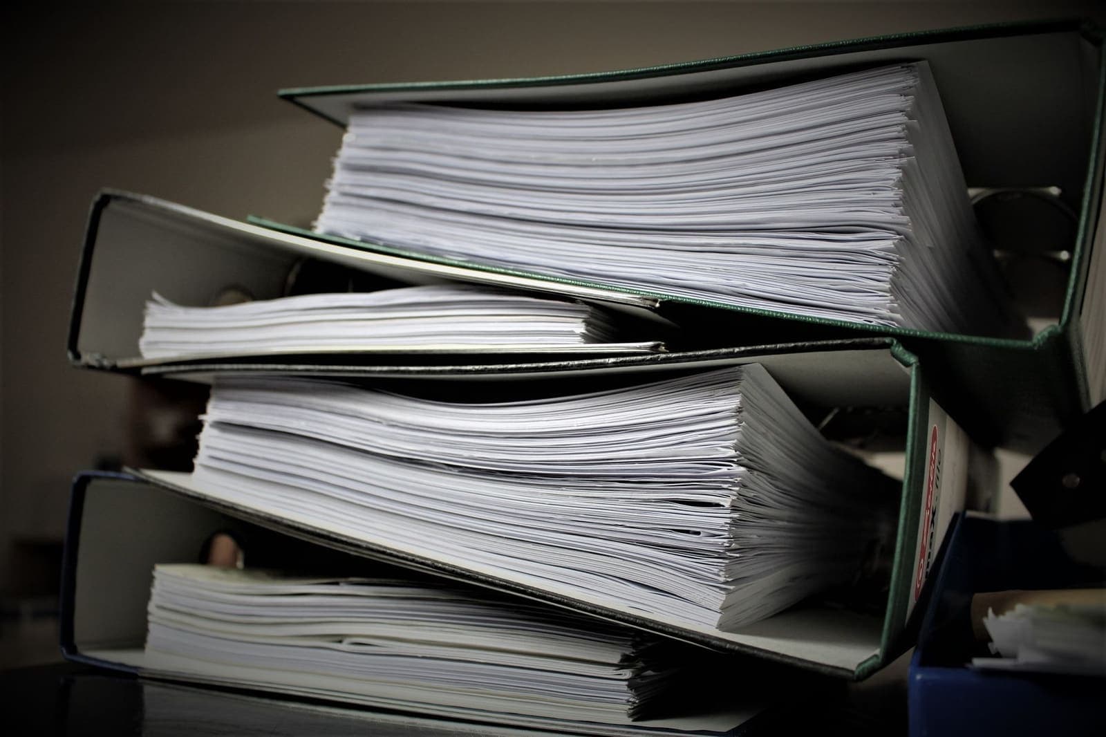 Three thick ring binders stacked and full of documents on a desk