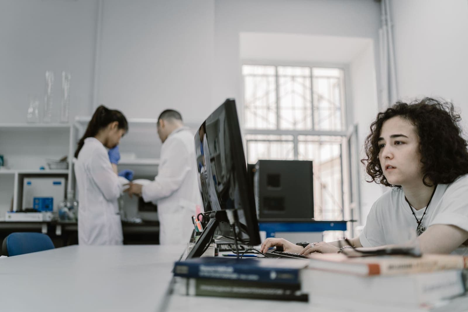 A research staff member working at a computer in a laboratory while two colleagues work behind her