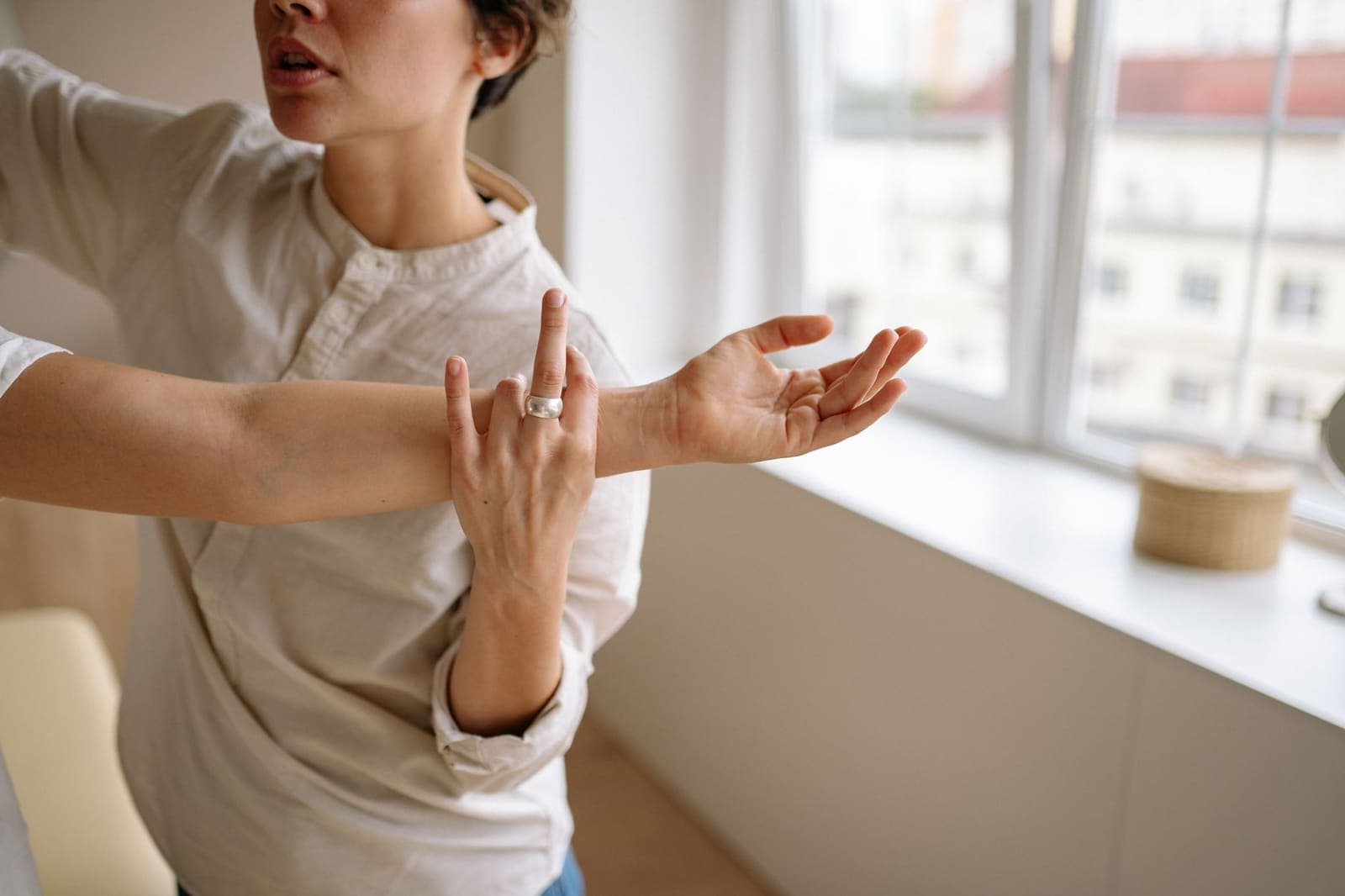 A practitioner guides a patient's outstretched arm through a stretch beside a bright window