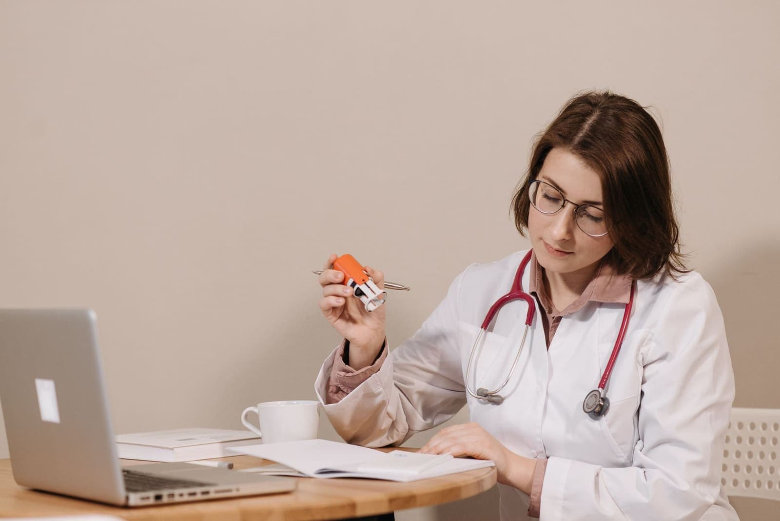 A clinician at a desk reviewing paperwork beside a laptop