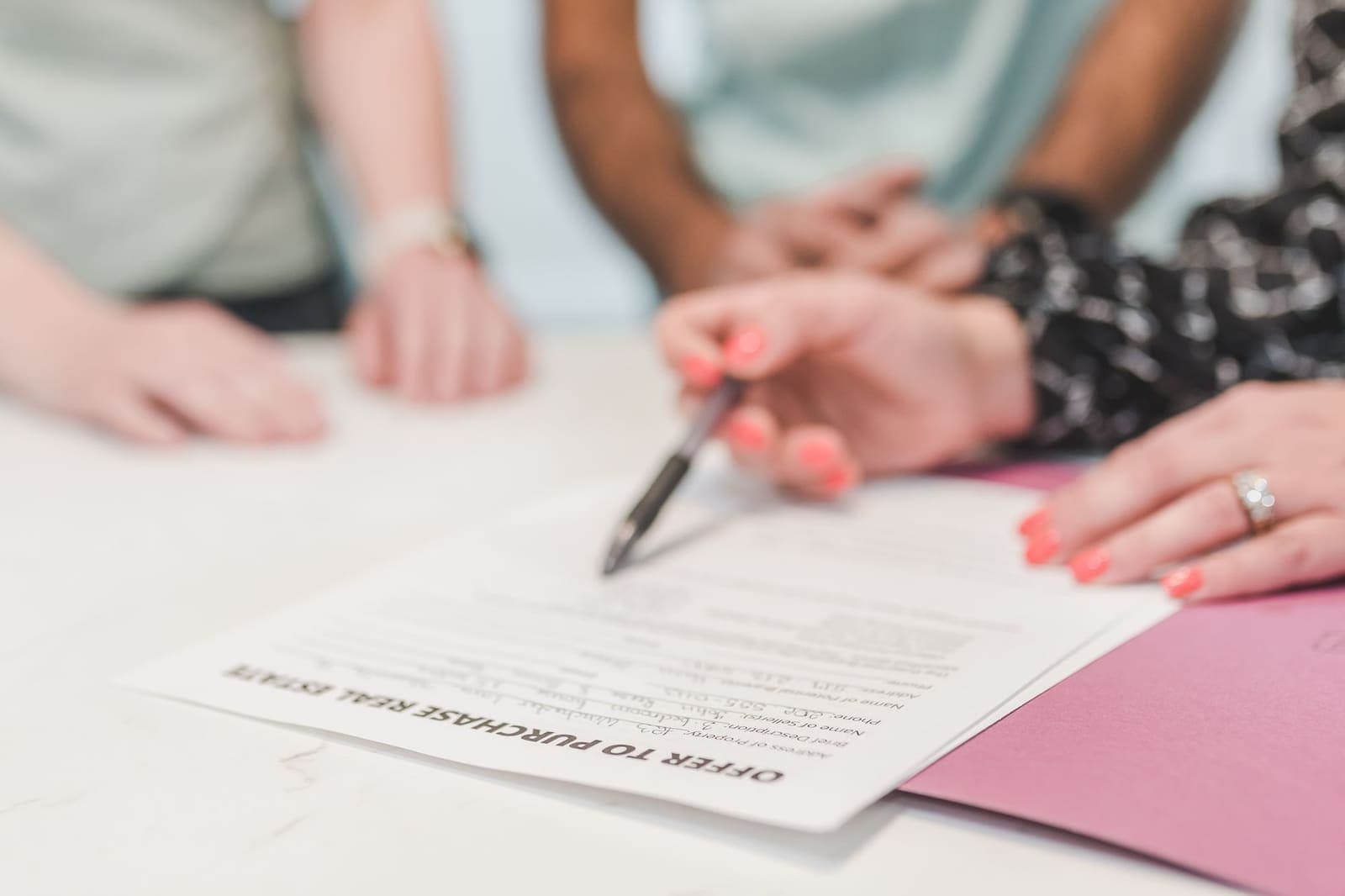 Close-up of hands at a table with a pen over a printed Offer to Purchase Real Estate form