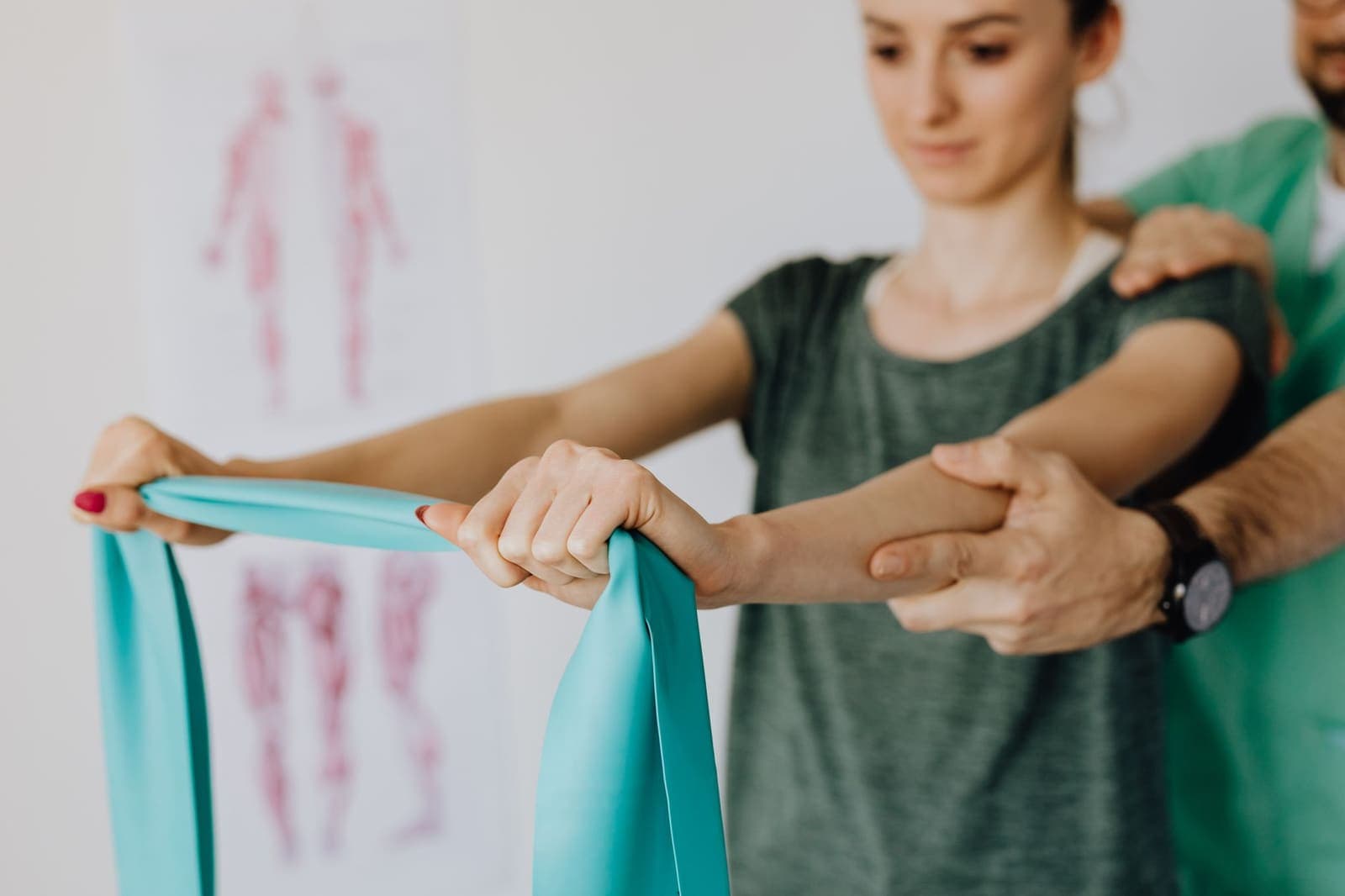 A therapist guiding a patient through a resistance band exercise in a treatment room