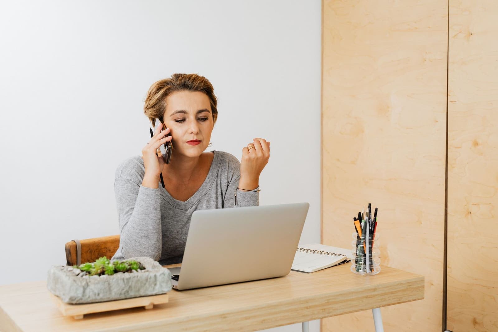 A woman on the phone at a desk with a laptop open