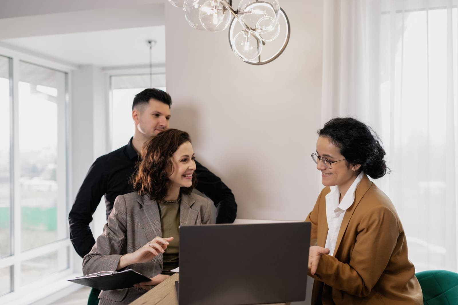 Three colleagues around a laptop in a bright office