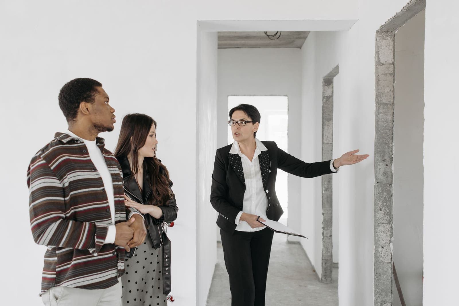 A real estate agent showing a couple through an unfinished home