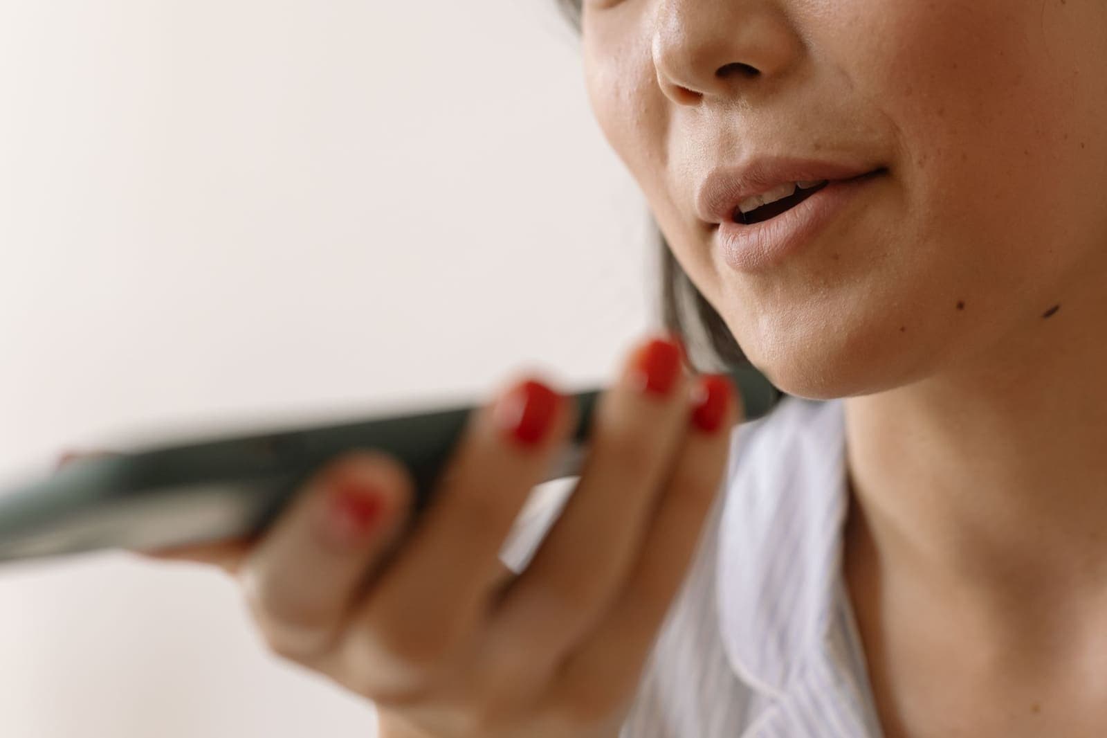 A close-up of a woman speaking into a phone held near her mouth