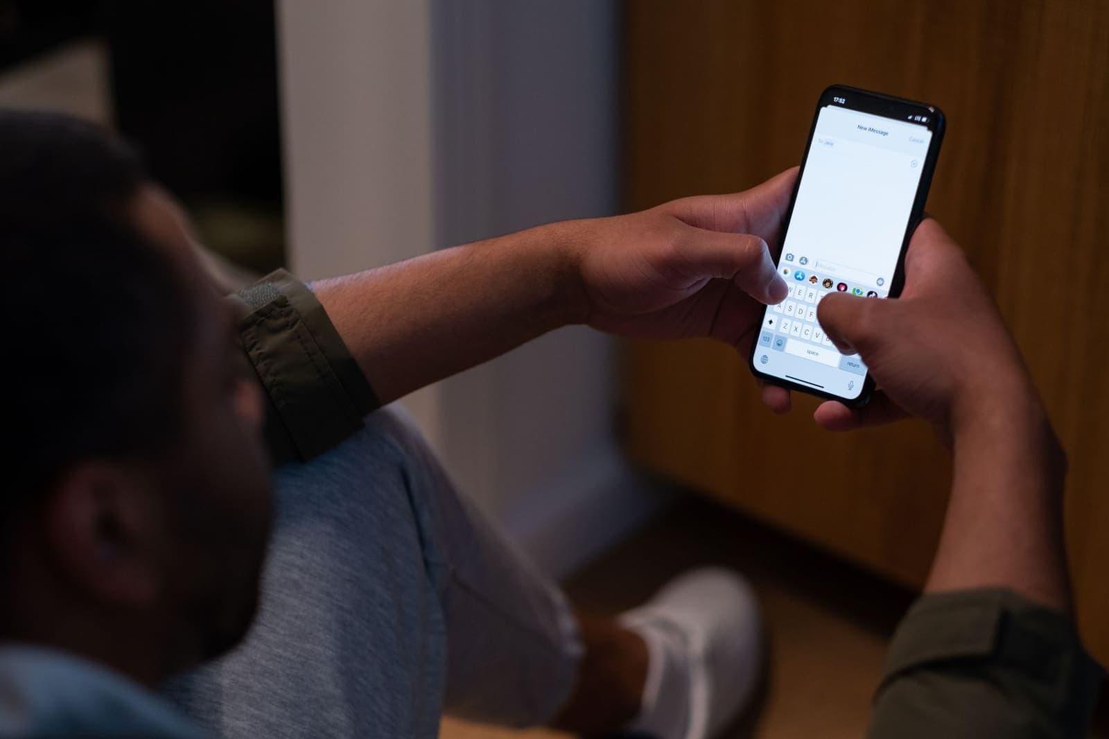 A man typing a message on his phone at home in the evening