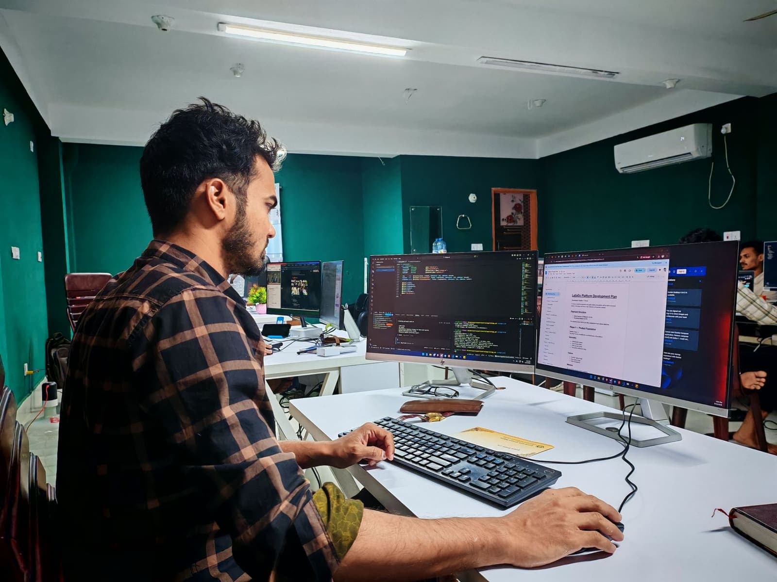 A developer working at two monitors in a small office