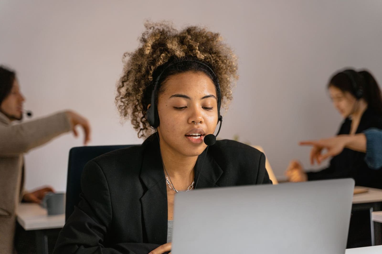 A support agent wearing a headset speaking while looking at a laptop