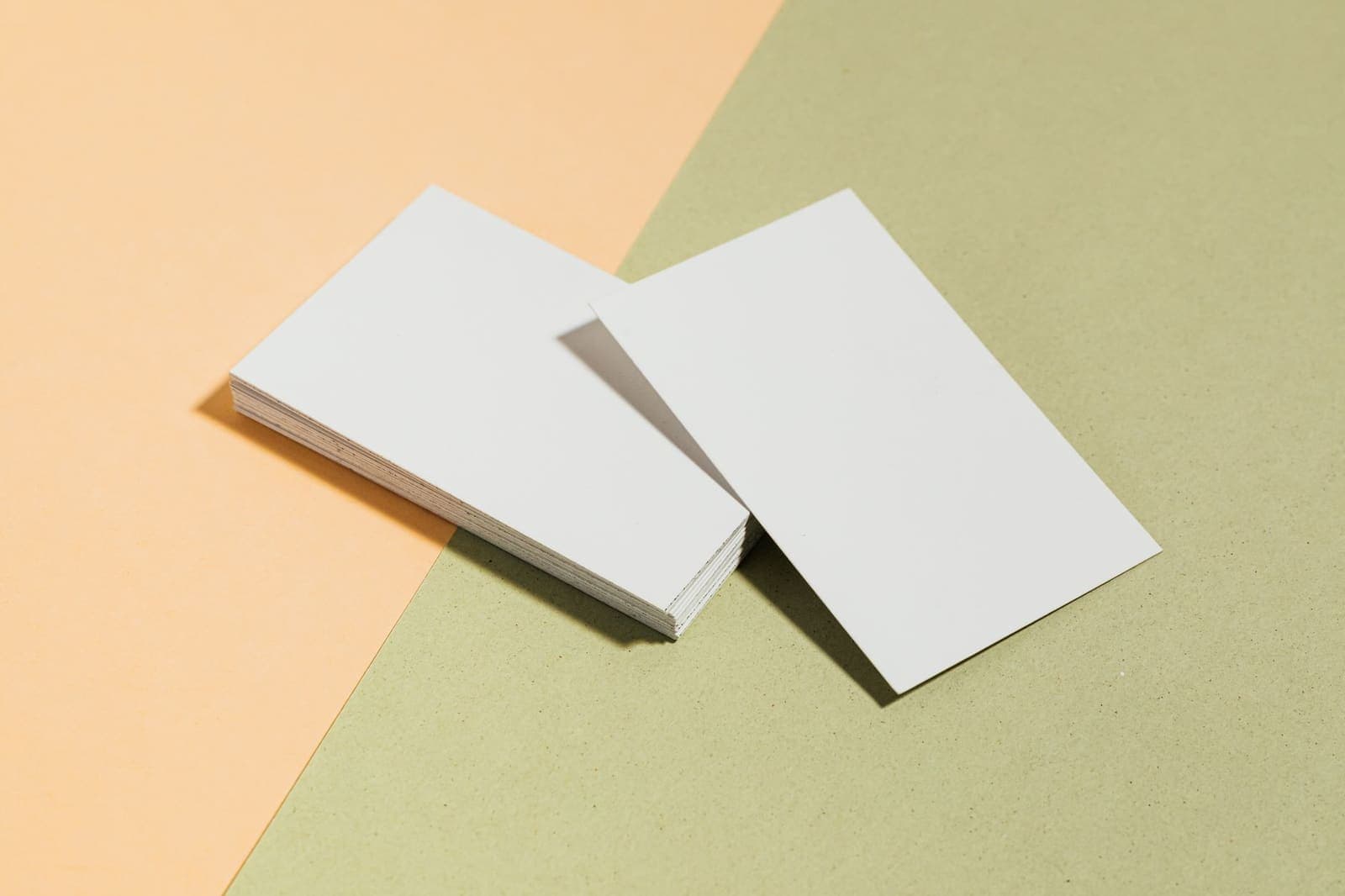 A stack of blank business cards on a two-tone pastel surface