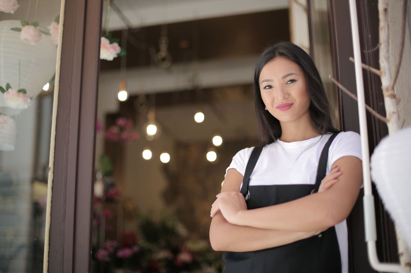 A shop owner standing at the entrance of her store with her arms crossed, smiling