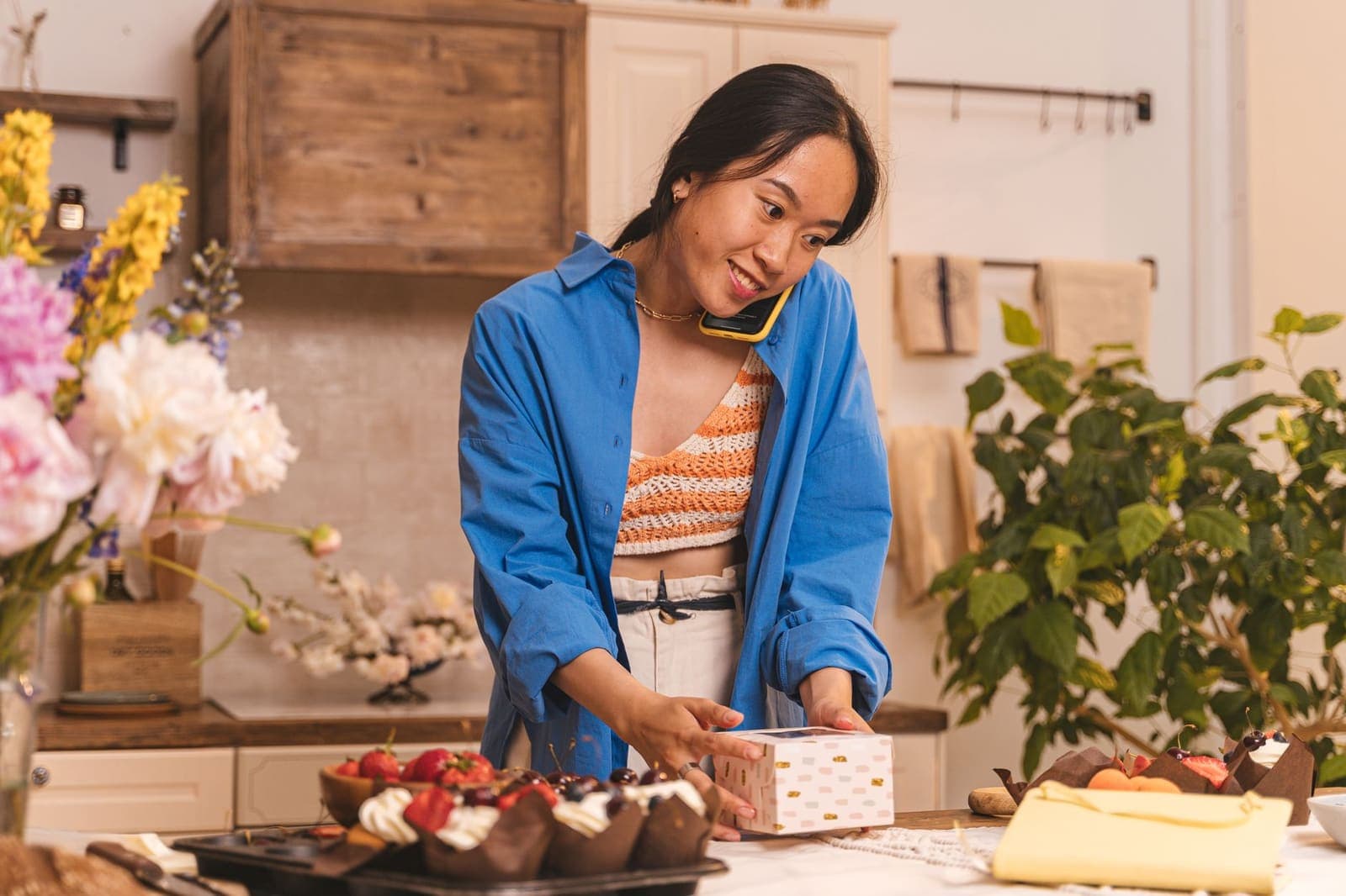 A bakery owner on the phone while boxing an order at the counter